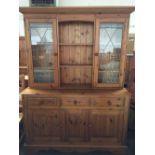 A pine dresser with plate rack and double cupboards with astragal glazed doors over three short