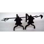 A pair of cast iron fire dogs with shield decoration together with a wrought iron fire fork with