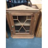 A pine corner display cabinet with carved pediment over astragal door,