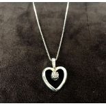 A silver square link chain with a gold plated heart pendant with a zirconia