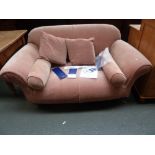 A Multi York two seater peach upholstered sofa raised on turned legs and castors,