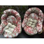 A pair of green rattan chairs with padded floral cushions together with another rattan chair with