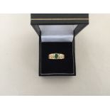 A 9ct gold ring hallmarked Birmingham 2003 with an Emerald surrounded with four diamond chips