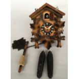 A Black Forest cuckoo clock with traditional wooden foliage design, white dial,