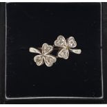 An 18ct gold ring with six diamond chips set into two three-leaf clovers,