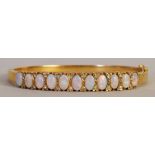 A 20th century 9ct gold ladies bangle set with eleven white opals