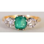 A gold emerald and two stone diamond engagement ring