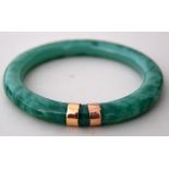 A Chinese mottled green jade and yellow metal mounted bangle of simple circular form,