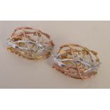 A pair of white and yellow metal clip earrings in the form of interlaced branches,