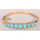 A 15ct gold ladies bangle set with nine cabochon turquoises interspersed with diamond chips