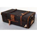 A leather and canvas travel trunk with leather strapping and travel labels and stickers,