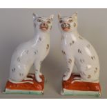 A pair of Victorian Staffordshire figures of cats seated on cushions, gilt enriched,