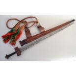 A sword with leather and metal hilt complete with a leather scabbard and ornamental red and green