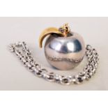 A mid-20th century silver apple pendant with a gilt metal leaf on a simple chain, EJ Ld,