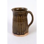 A green glazed jug with incised fluted patterning,