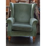 A green upholstered wing back armchair