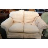 A cream coloured two seater sofa with loose covers
