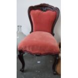 A late 19th century saloon chair with carved edging upholstered in red