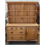 A pine dresser with a plate rack of two shelves over two short drawers over two long drawers beside