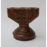 A carved wooden candlestick holder with space for three candlesticks and carved geometric pattern