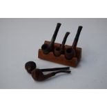 A collection of five tobacco pipes, one marked 'Carey Magic Inch', one 'Franklin',