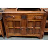 A mid century sideboard with two drawers over two cupboard doors with foliate carving