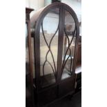 A glass fronted display cabinet with curved top,