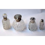 A collection of crystal cut bottles, mostly scent lidded bottles with silver rims,