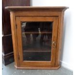 A glass fronted pine corner cupboard with two interior shelves