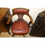 An oak and red leather upholstered swivel office c