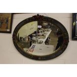 A Barbola style oval wall mirror with floral decor