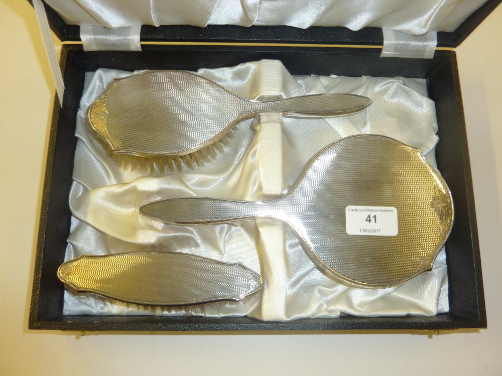 A silver three piece dressing table set