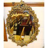 An ornate gilt framed oval wall mirror