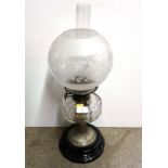 A brass and glass oil lamp with clear glass reservoir