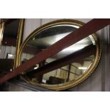 A gilt framed oval and bevel edged wall mirror