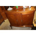 A mahogany bow front side cabinet raised on cabrio