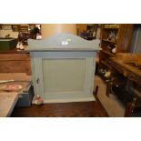 A green painted wooden single door wall cabinet