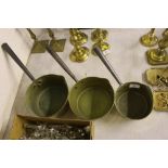 A set of three brass graduated saucepans with iron