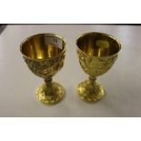 A pair of gilded goblets with cherub, grape and vi