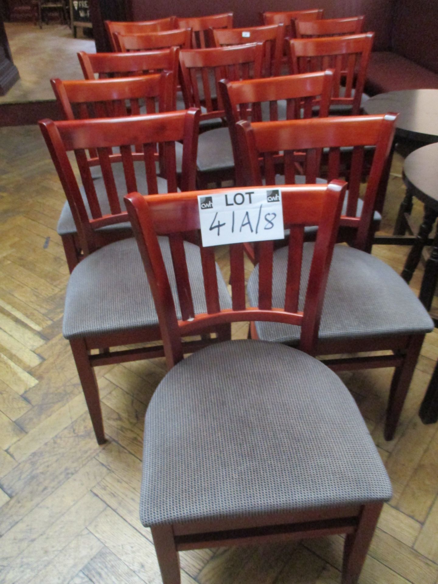 9 x medium stained wood dining chairs with grey patterned seats.