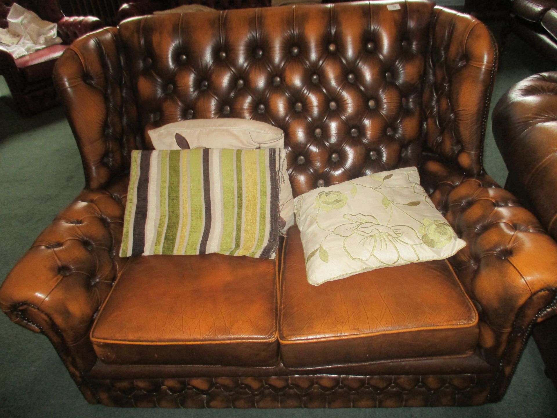Brown leather two seater wing back deep button back Chesterfield settee.