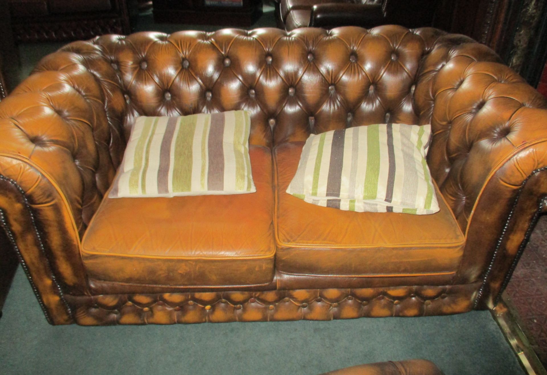 Brown leather two seater roll arm deep button back Chesterfield settee.