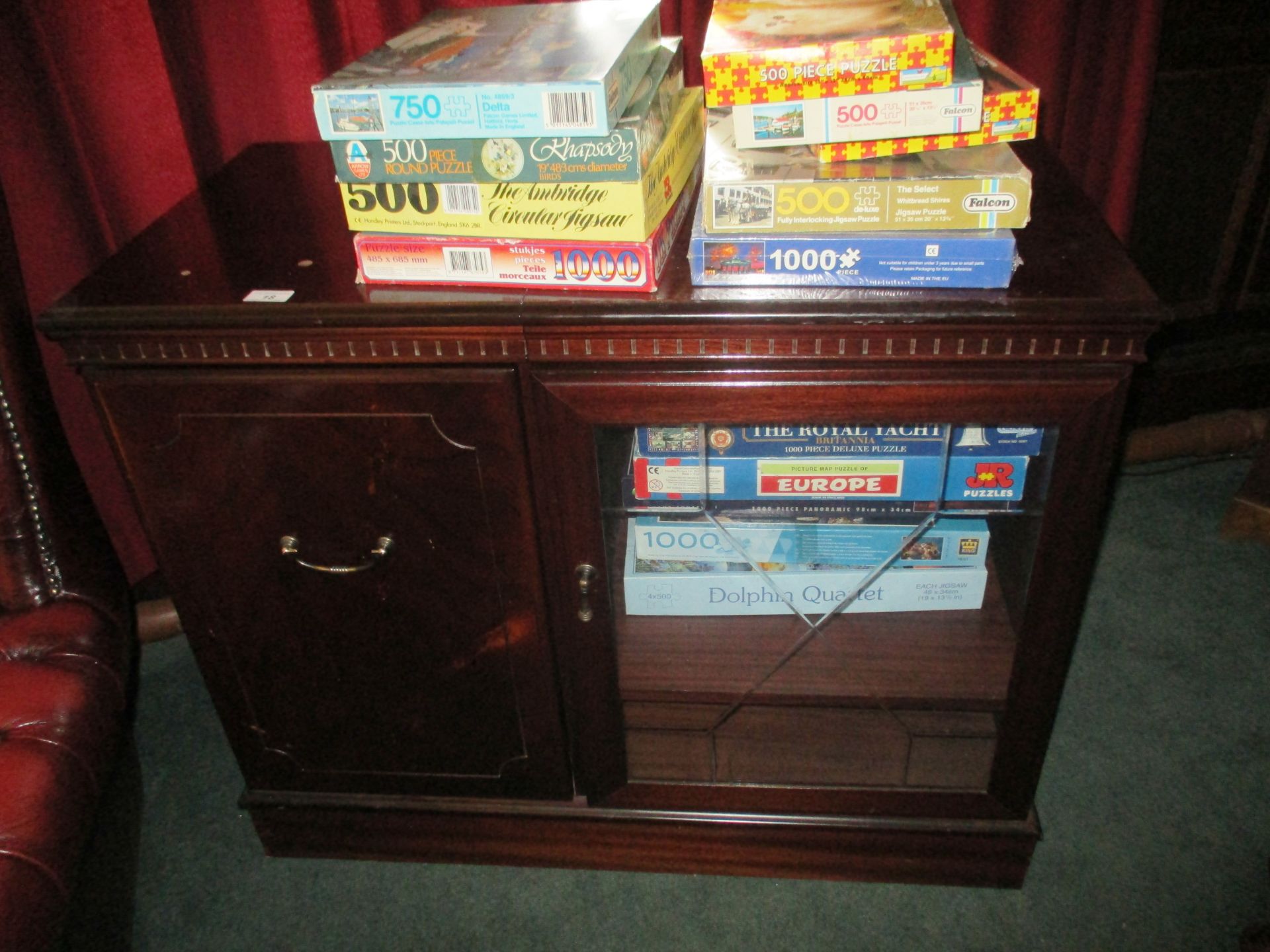 Mahogany finish television stand and a quantity of jigsaws/games.