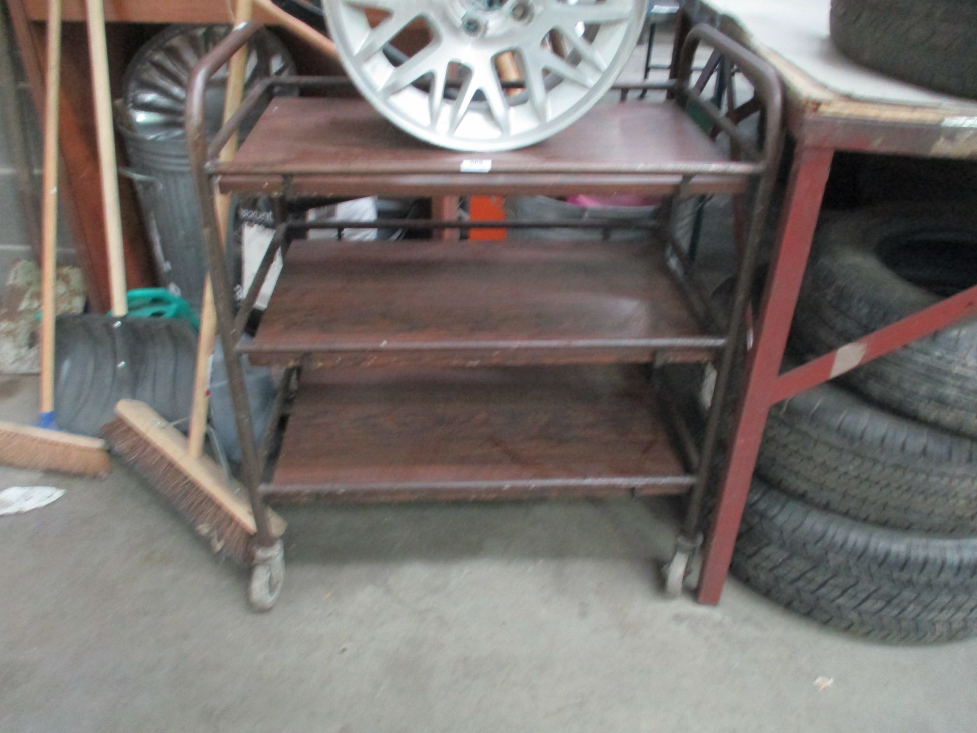 A brown metal 3 tier mobile trolley