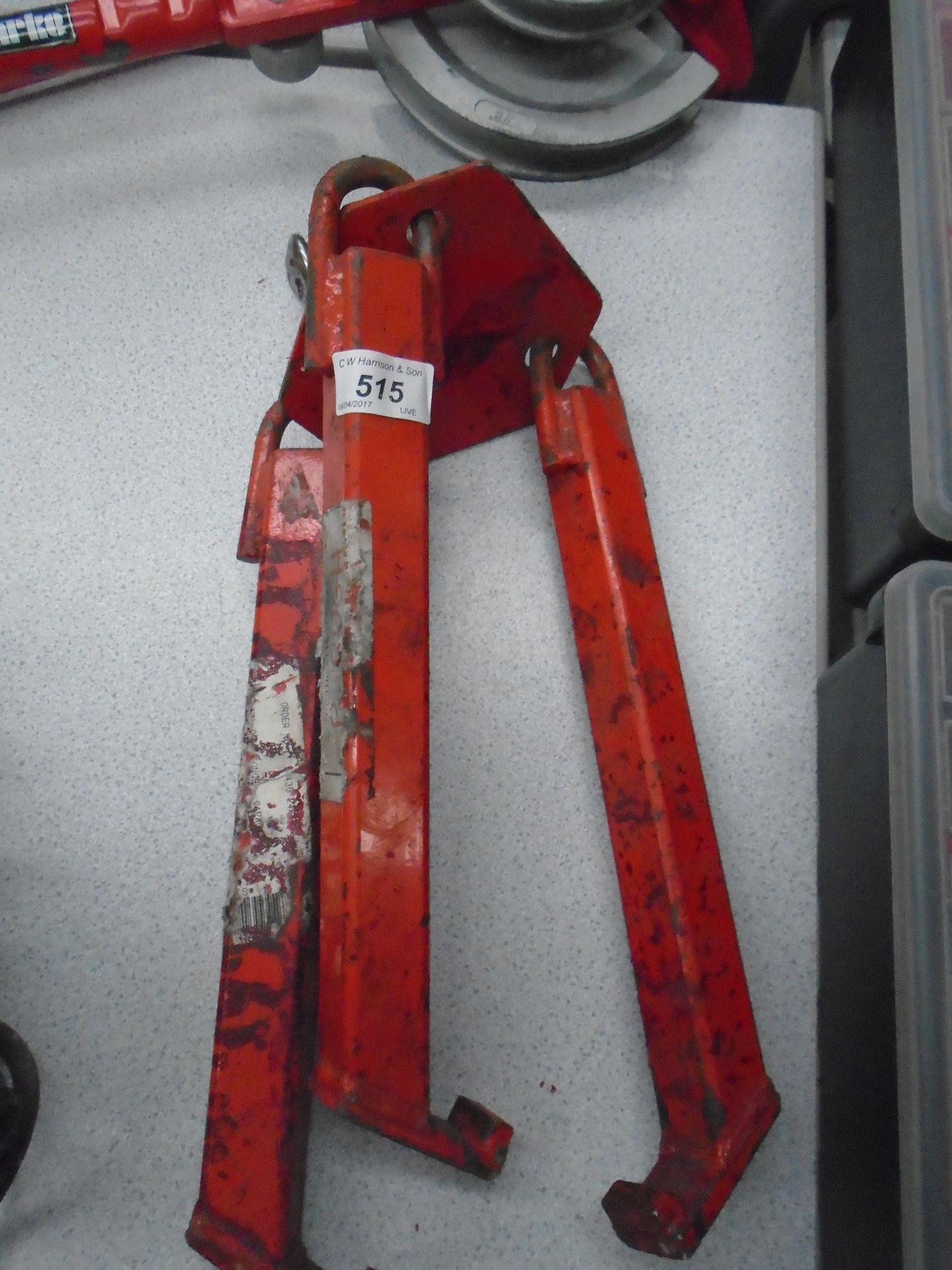 A red metal 3 leg lifting barrel clamp