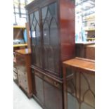 A mahogany reproduction bookcase/wall unit with double astragal glazed doors over a 2 drawer 2 door