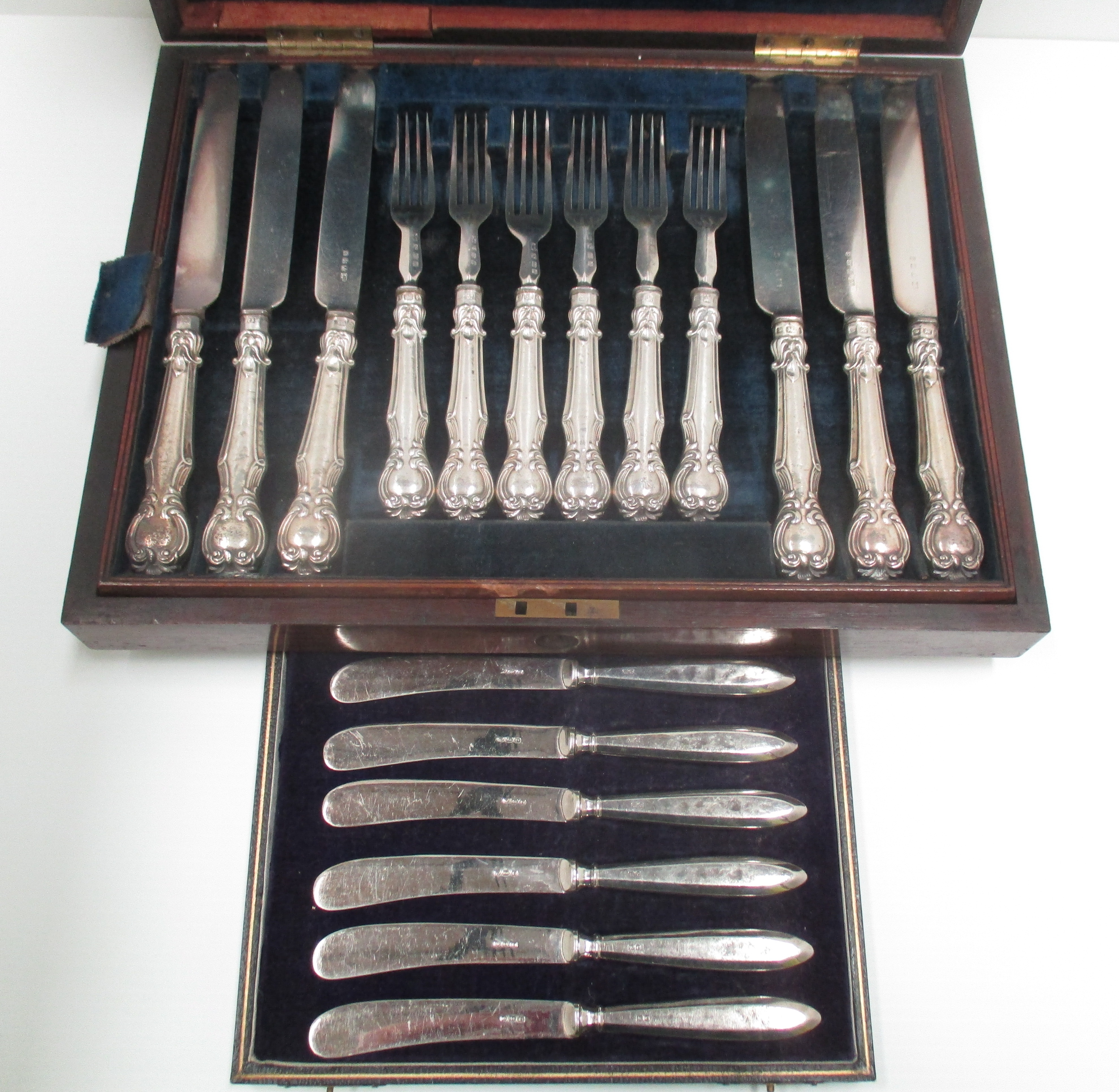 A set of twelve pairs of Victorian dessert knives and forks with embossed silver cased handles in