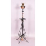 A wrought iron and copper telescopic standard oil lamp of scroll form, on four spread feet.