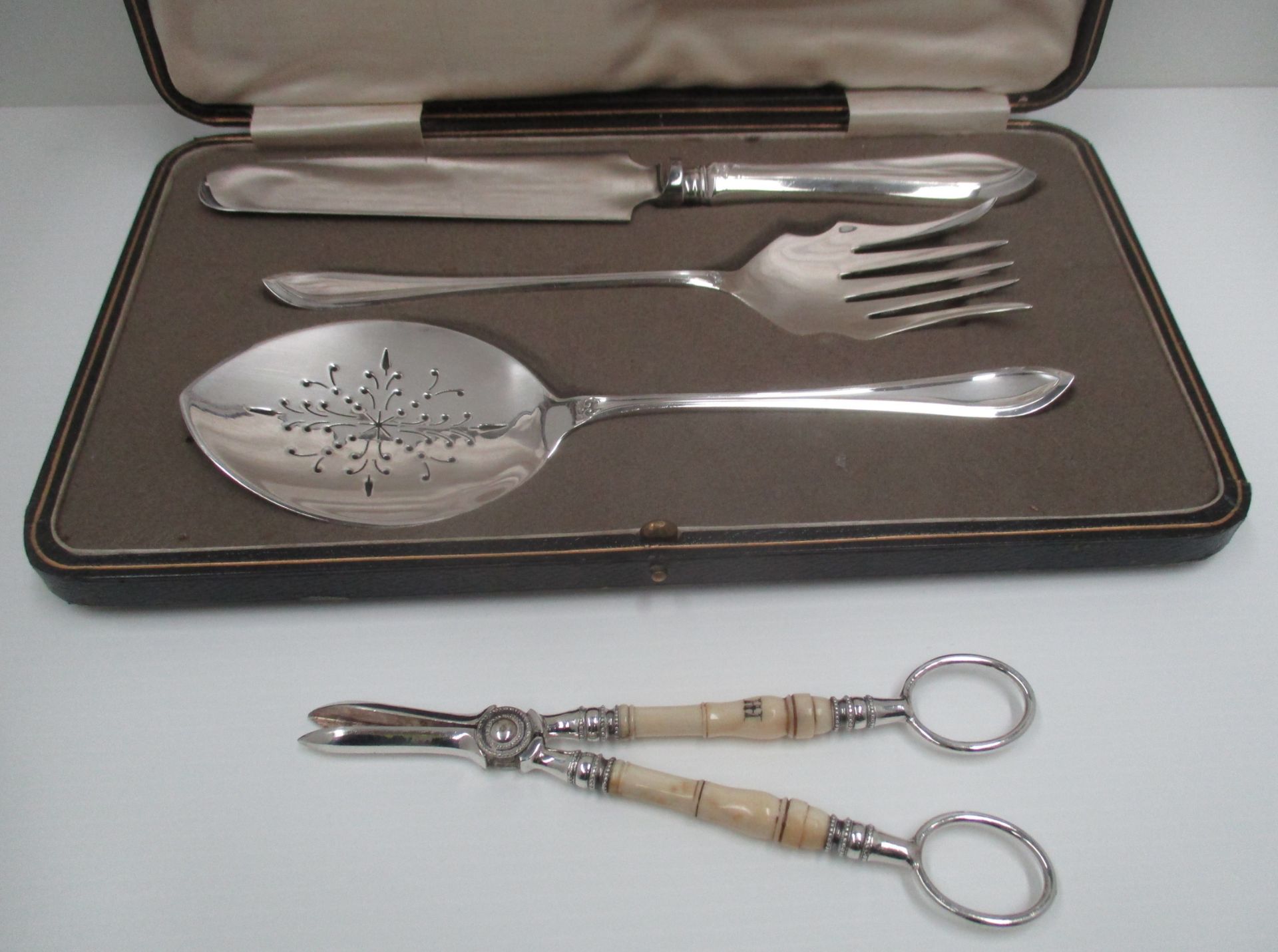 An electroplated three piece confectionery serving set in fitted case and a pair of grape scissors.