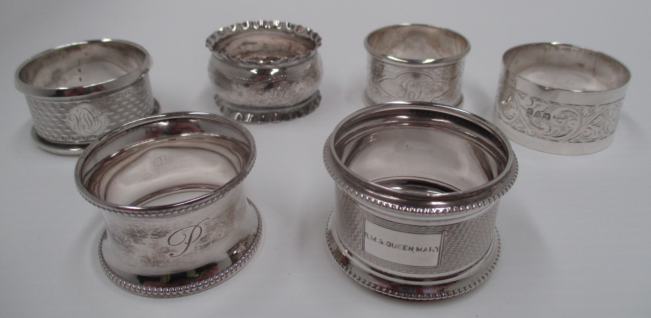 A silver napkin ring with engine turned decoration, engraved R.M.S.